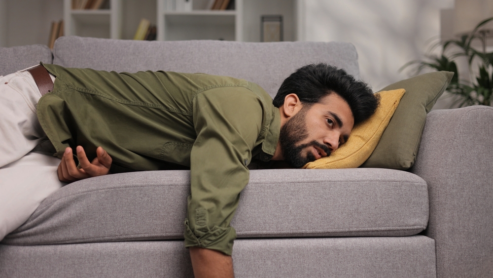 A tired Indian man crashes on the couch.
